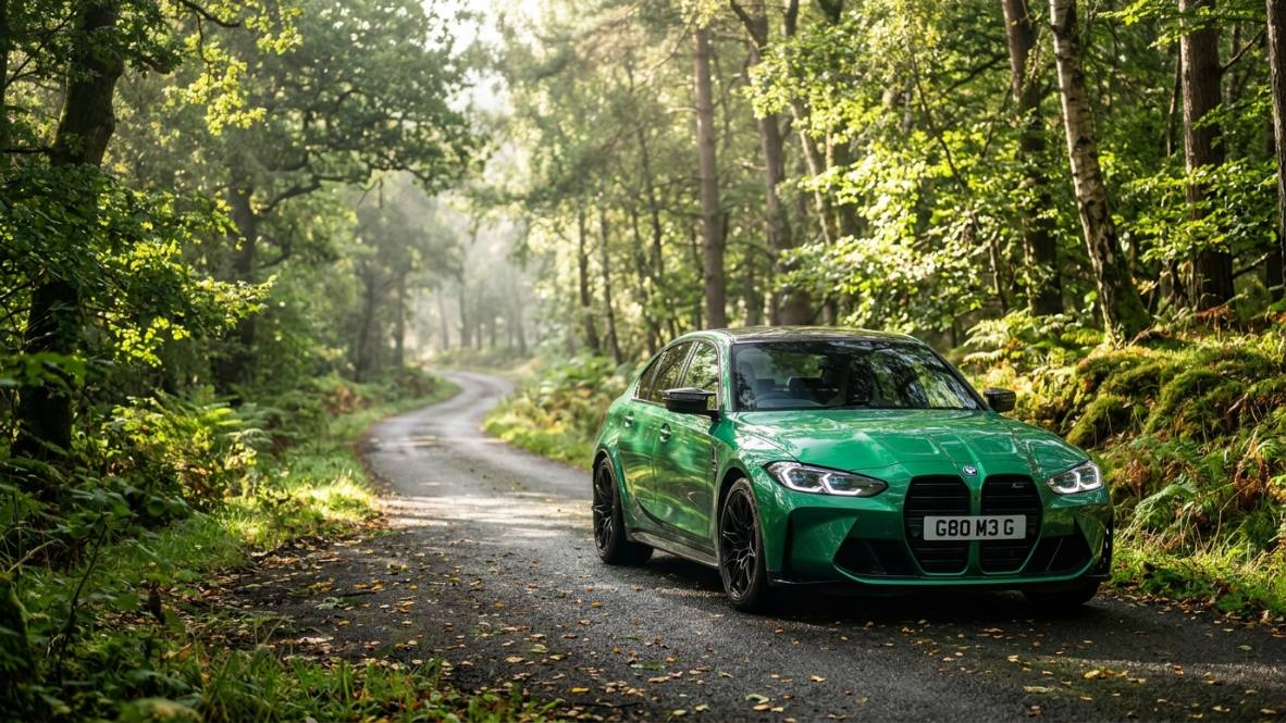Green BMW M3 on a sun-dappled forest road