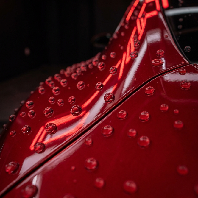 Water beads standing on deep red paint