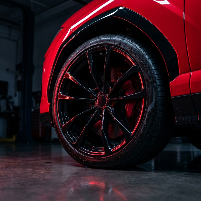 Macro of a gloss black wheel and caliper in red light
